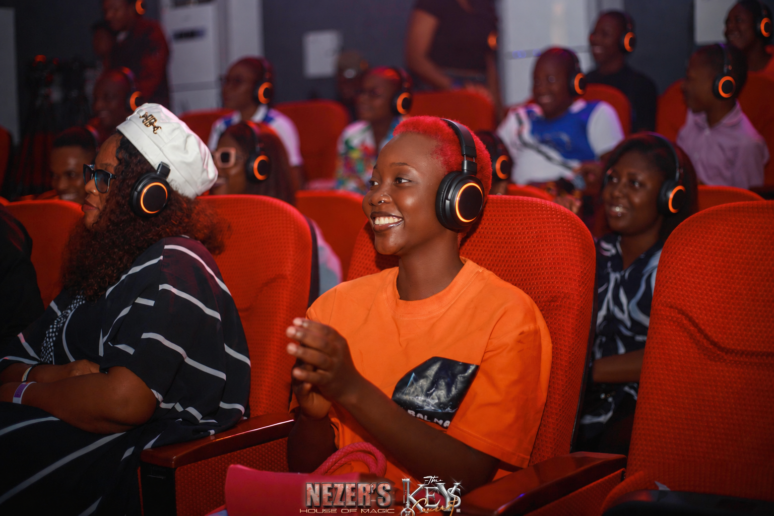 Audience wearing orange-lit headsets in an edited Nezer House of Magic event photograph
